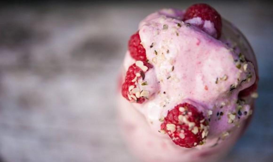 Rosa Nicecream im Glas mit Himbeeren und Hanfsamen als Topping
